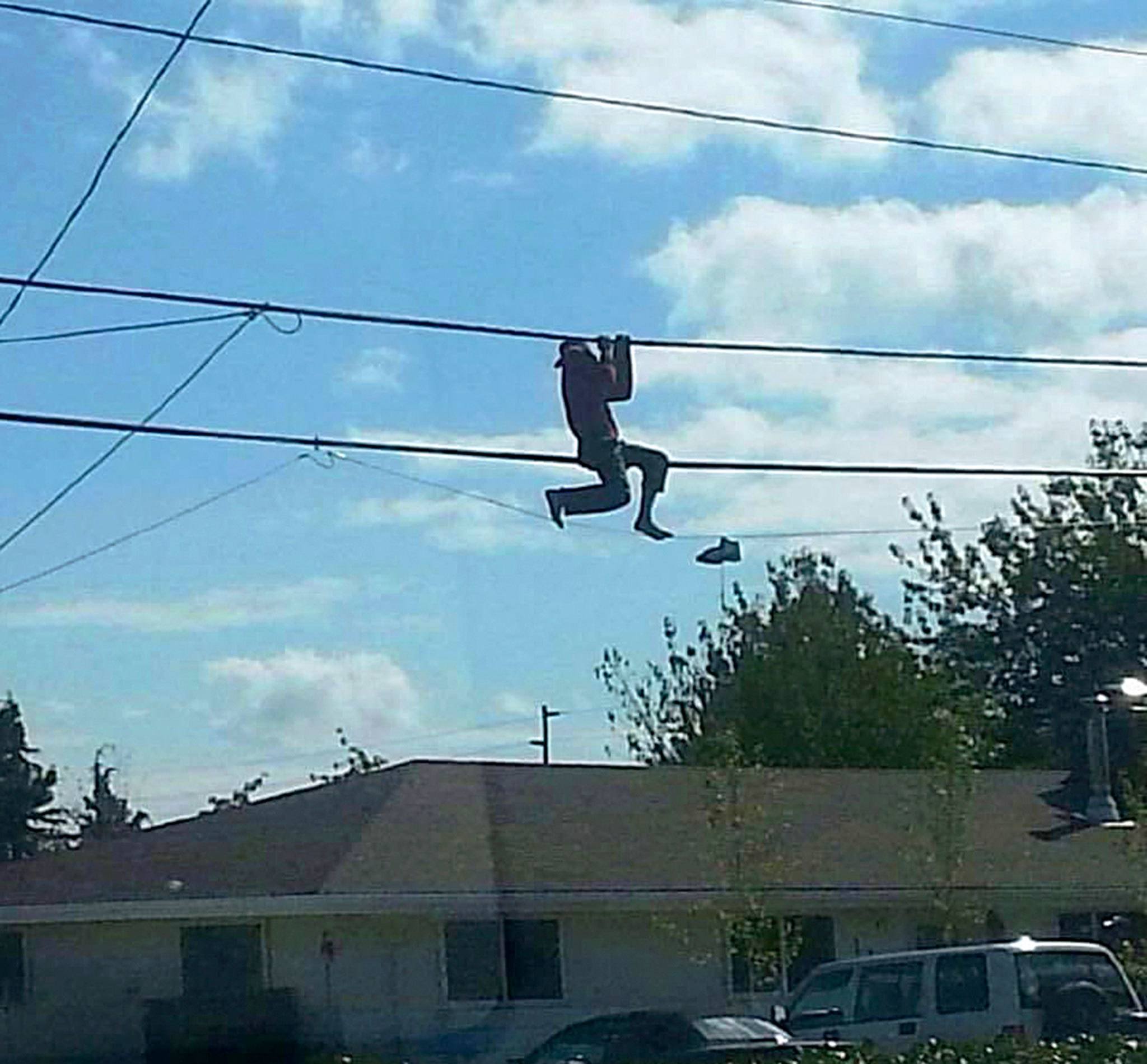 A shoeless man hangs from phone lines on North Oak Harbor Street Sunday. He told rescuers that he was trying to retrieve a pair of shoes. Photo by Robert Rizzo