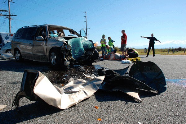 Emergency responders attend to one of three men injured in a car accident that occurred at the intersection of NW Broadway and Highway 20 Thursday afternoon. The crash closed that section of road for more than an hour.