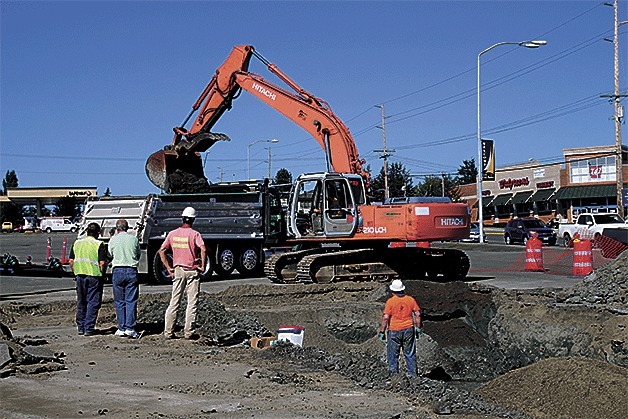 Workers remove contaminated dirt from the site of the former Ford dealership in Oak Harbor.