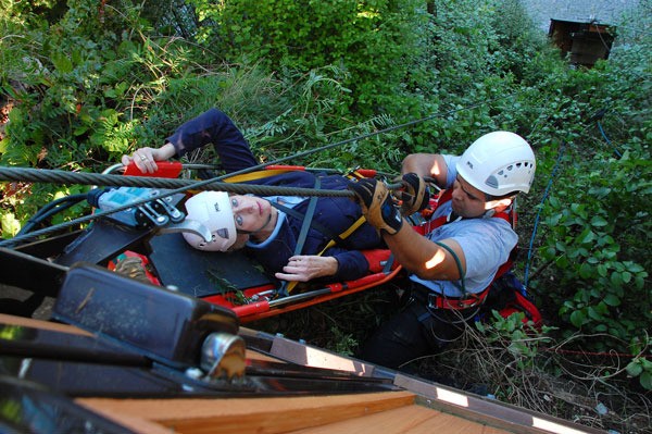 Oak Harbor Firefighter Rich Cuevas assists as Greenbank resident Sheilah Chidsey is hoisted to safety from the cliff in front of her high bank home on North Bluff Road. She was riding a gondola from the beach Sunday when one of the cables broke.