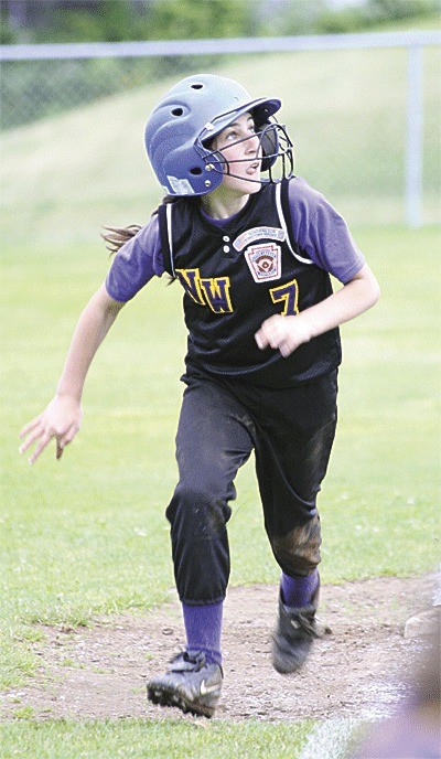 Jules Toney watches a fly ball as she races home for a run.