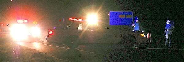 Washington State Patrol officers walk past patrol cars at the intersection of Ebey Road and Highway 20 Thursday evening. A Coupeville woman