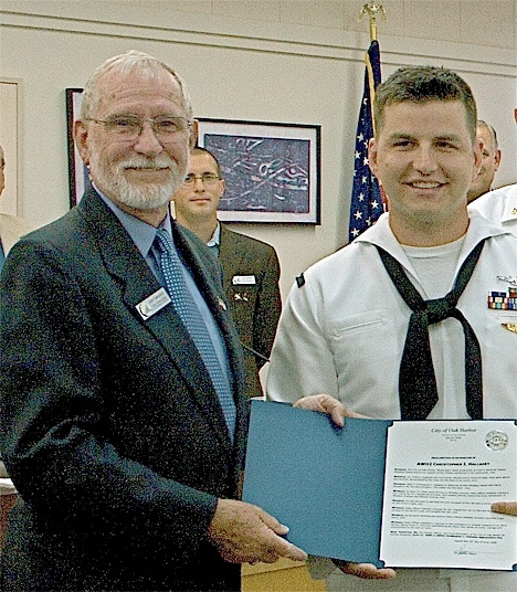 Oak Harbor City Councilman Jim Campbell recognizes Chris Halladey for a heroic deed. Halladey stopped a runaway van with a young child inside from rolling into the busy intersection of Whidbey Avenue and Midway Boulevard.