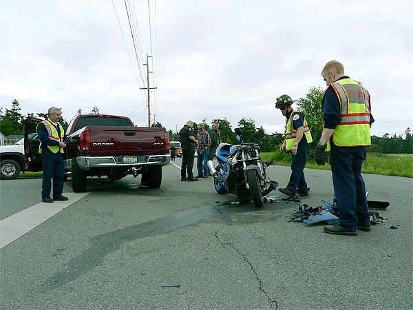 A wrecked motorcycle and debris lie next to a pickup after a collision Tuesday afternoon at the intersection of Wanamaker Road and Prairie View Avenue near Coupeville on Whidbey Island. A woman