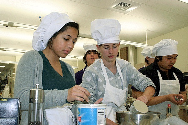 Oak Harbor High School students Bianca Blake and Rebekah McDaniel learn how to make biscuits in culinary arts class. They may have fewer days to practice their cooking days if the school year is reduced