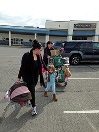 Stephanie Decker and 3-year-old daughter Isabel are helped out to their car with commissary employee Kim Cleveland Thursday.