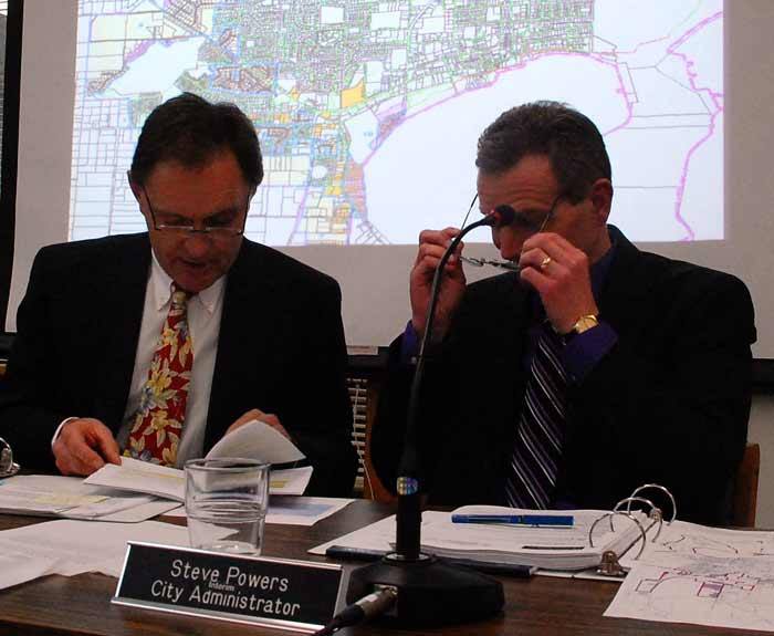 Oak Harbor City Attorney Bill Hawkins and interim City Administrator Steve Powers consult city rules at a city council meeting this month when Mayor Scott Dudley was called to break a tie vote concerning Driftwood Beach Addition’s proposed local improvement district.