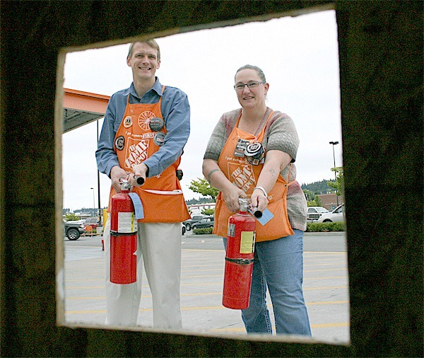 Home Depot Store Manager and Team Depot Captain for the district James Croft and Team Depot Captain Liz Bennett practice their fire extinguisher skills in preparation for the Fire Safety event Saturday