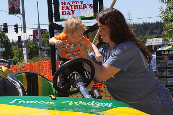 Adrienne Sandall places her 1-year-old son Nicholas into the cockpit of a racing boat on display at Flyers Restaurant Saturday. Hydroplane racing in Oak Harbor takes place Aug. 16-17.