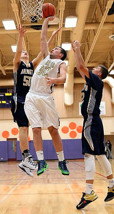 Oak Harbor's Jake Sturdevant attempts to tip in a ball over Arlington's Jeremy Bishop