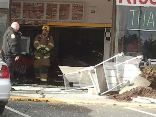 A fireman walks out of Little Caesars Pizza in Oak Harbor after a car drove through the front doors.