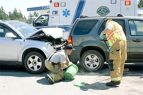 Firefighters clean up fluids leaking from two of the four vehicles involved in a collision in Oak Harbor Tuesday afternoon.