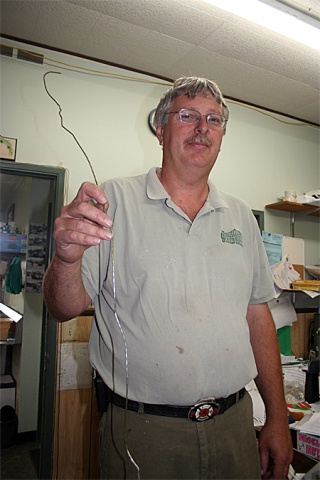 Greenhouse Florist and Nursery co-owner Henry Vandenhaak holds the bent hanger thieves used to fish bags of money out of the deposit slot on the business's safe. The burglars got away with at least $3