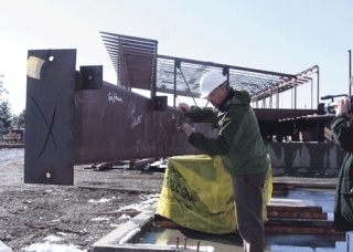 Oak Harbor High School principal Dwight Lundstrom signs the final beam at Thursday’s “topping off” ceremony. He was joined by students