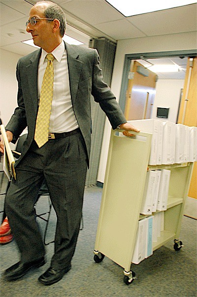 Island County Prosecutor Greg Banks wheels in a cart loaded with documents from a murder case to the commissioners’ work session. Banks is asking for additional funding for staff to help address a large workload.