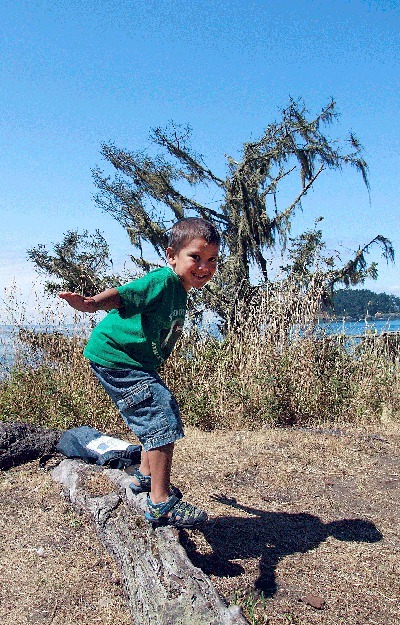 J.M. Shira of Kent surfs on driftwood at Deception Pass State Park’s West Beach Saturday during Washington States Park 100-year anniversary celebration.