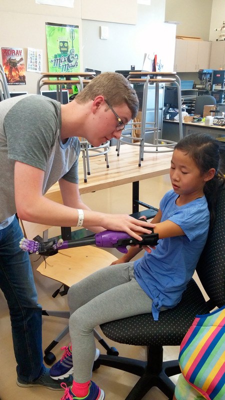 Oak Harbor High School student Michael Uttmark fits Jaelyn Crebbin with her robotic arm. Uttmark led the project to create the prosthesis.