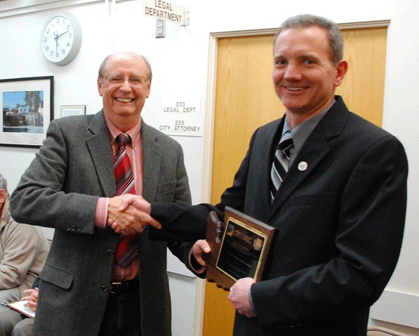 Richard Hart with the Washington Chapter of the American Planning Association presents Development Services Director Steve Powers with an award on SE Pioneer Way at a recent city council meeting.