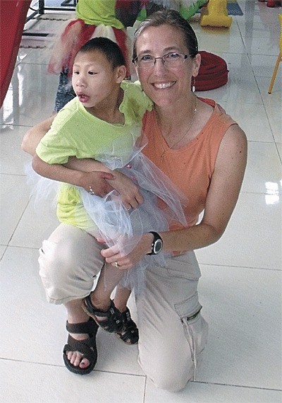 Toni Crebbin takes time to share with a special-needs orphan in Chaoyang