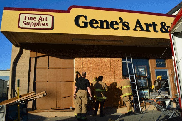 Firefighters cover a hole in the front of Gene's Art and Framing Tuesday. A woman accidentally drove her car into the store.