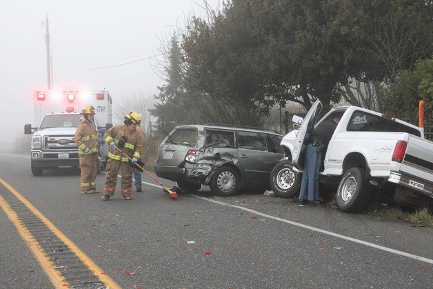 Firefighters from North Whidbey Fire and Rescue sweep up after a two-car collision on State Highway 20 in San de Fuca Friday morning.