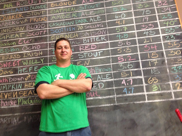 Whidbey Island Brew Supply store owner Robbie Skillin stands in front of the list of his beer recipes available for purchase.