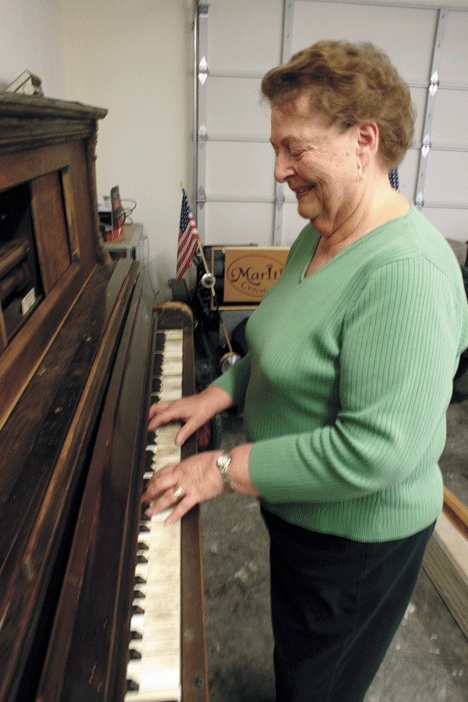 Joanne Engle Brown plays with a player piano that will be sold at auction July 25. It was used in the silent film era.