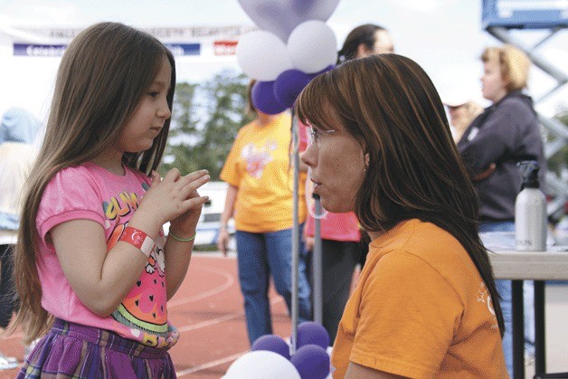 Oak Harbor hair stylist Naomie Robinson consults with 6-year-old Piper McMahan before a haircut June 1 at the Relay for Life of Whidbey Island event. McMahan's hair was cut as part of a hair donation drive to make real-hair wigs for cancer patients.