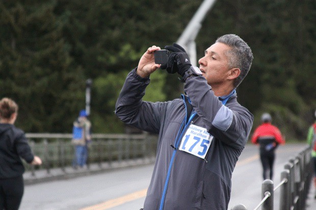 A participant in the 2013 Whidbey Island Marathon stops on Deception Pass bridge to take a photograph.