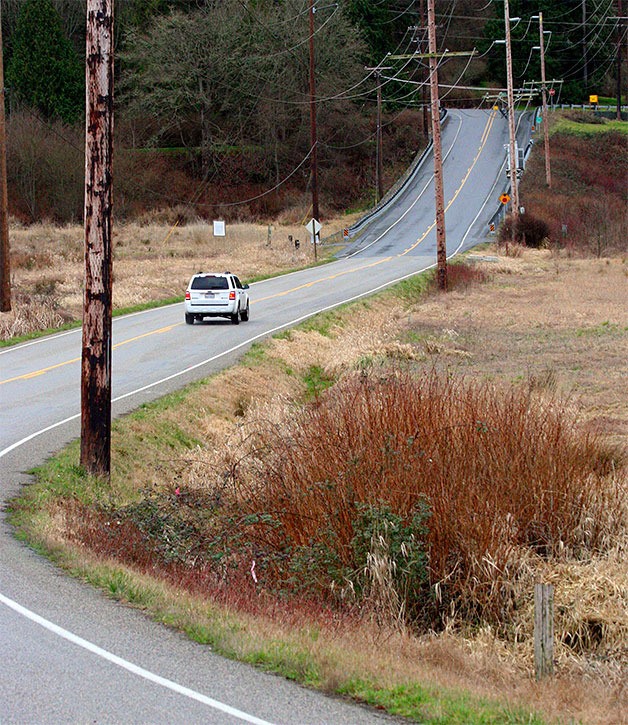 An SUV drives south on Dike Road on the portion that will be raised this summer in a project that will also restore salmon habitat.