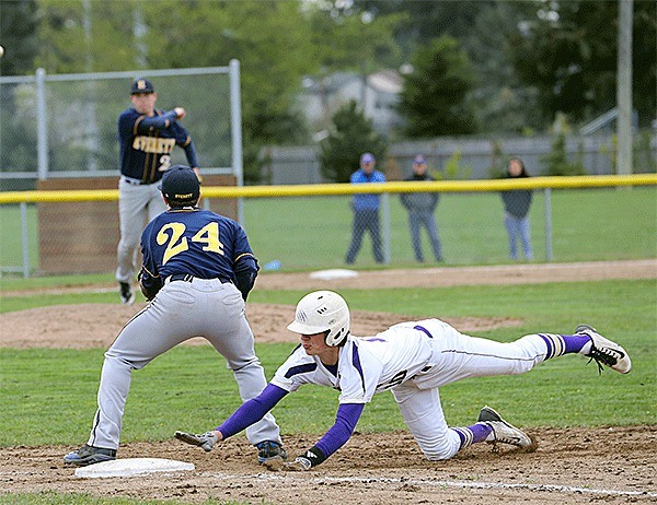 Oak Harbor's Preston Rankin dives safely back into first base on a pick off attempt as Everett's Gabe Maggio throws to first baseman Lewis Elliott.