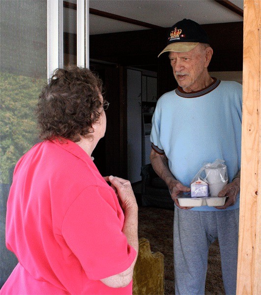 Oak Harbor resident Rodd Beardsley receives a meal from Meals on Wheels volunteer Diana Spear.