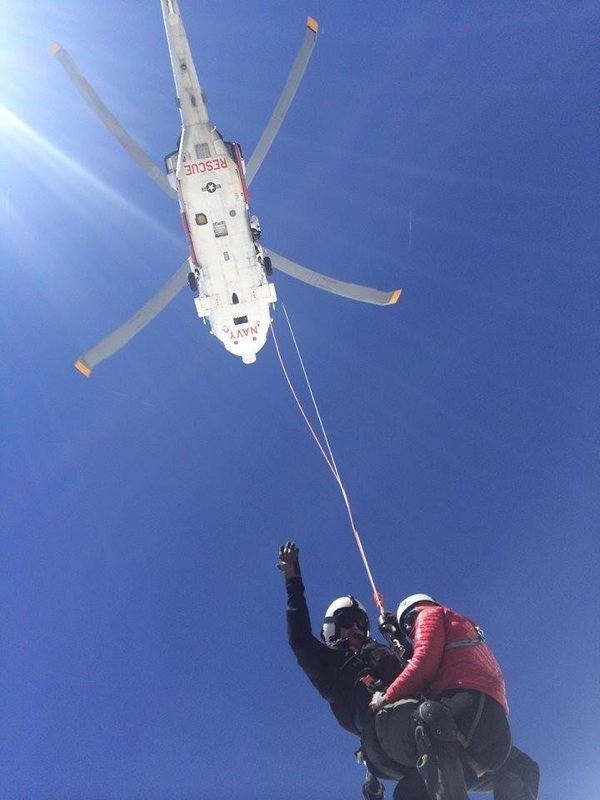 A Search and Rescue team member from Whidbey Island Naval Air Station lifts an injured woman from Mount Stuart Thursday.