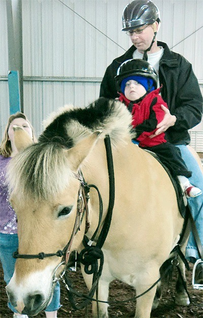 Hippotherapy provider Ray Perry works with Jacob Smith to improve his motor skills with the help of EqX’s Haldor