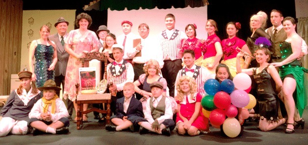 The Whidbey Playhouse cast of “Gypsy” stands with the chair they set up as part of the Julia’s Chairs movement to remember a beloved community theater stage manager.