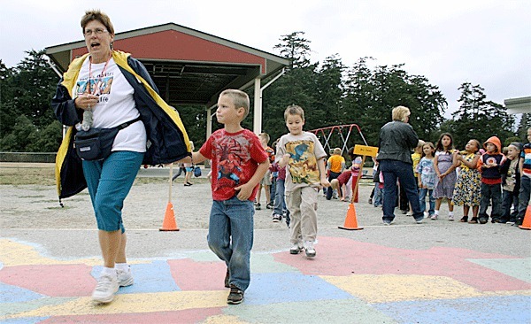 Coupeville Elementary School paraprofessional Callie Harvey escorts first-graders Alex Hutson and Jesse Cowan to class. The school district is enjoying higher-than-expected enrollment numbers