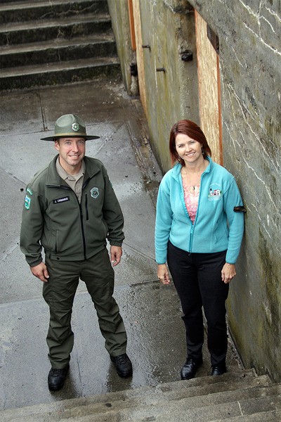 Jon Crimmins and Sharon Sharpe of Washington State Parks stand before the entrance to Battery Reuben Turman.