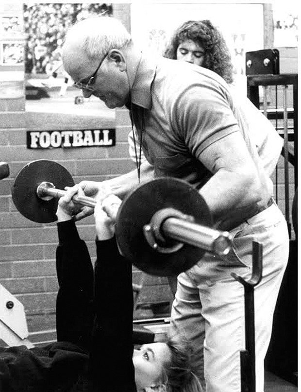 Duck Daugherty assists a student during a weight training class. The longtime PE teacher inspired students to push their physical limits.