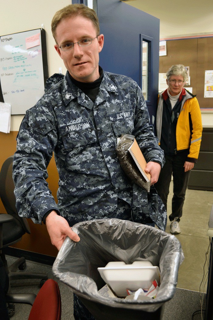 AZ3 Stephen Anderson holds up a trash can in his office at Fleet Readiness Center Northwest. He pointed out that everything in the trash can was recyclable. Anderson has spearheaded an aggressive recycling program at FRCNW.