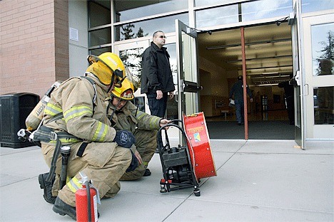 Firefighters set up a fan near an entrance to the Student Union Building Monday to clear out smoke from a small fire at Oak Harbor High School.