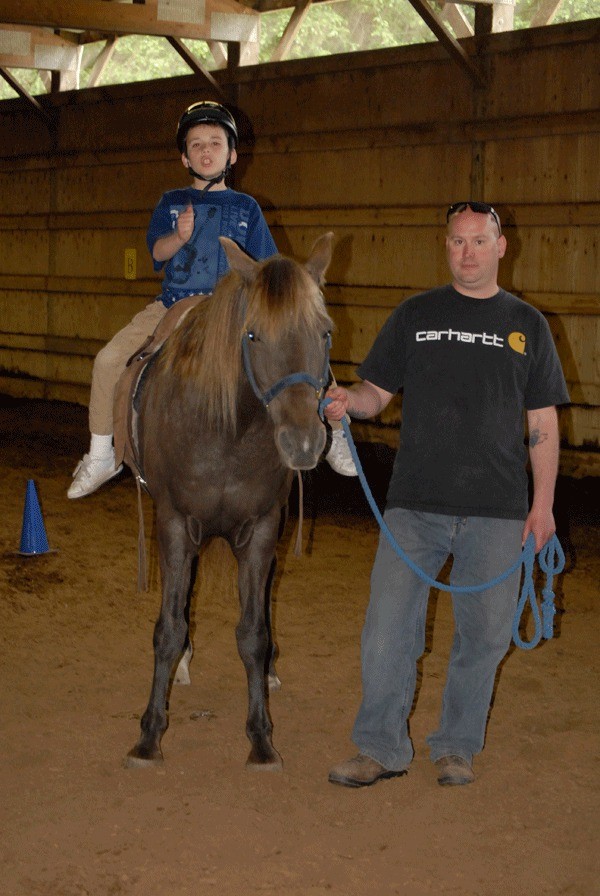 Tanner Watson learns with horse Bandit and volunteer Andrew Cummings at HOPE Therapeutic Riding Center.