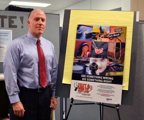 Supervisory Special Agent James Campbell stands by one of Naval Criminal Investigative Service’s new posters promoting NCIS’ new anonymous crime tip line.