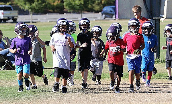 Oak Harbor Youth Football players jog to warm up.