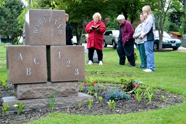 Members of the Navy Wives Club of America gather round Tuesday evening for a short dedication ceremony for the Babyland section of Maple Leaf Cemetery. The group has tended to that portion of the cemetery for many years