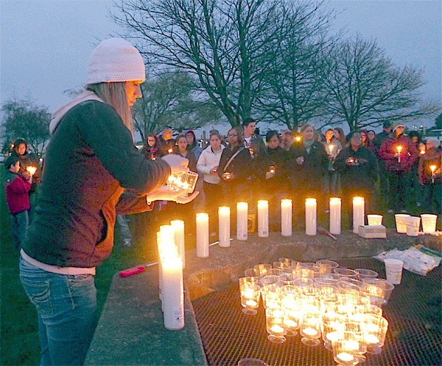 Tina Wieldraayer-Provoncha grabs candles to hand out to mourners who attended a candlelight vigil Monday night to pay respects to three Navy aviators who died in a plane crash.