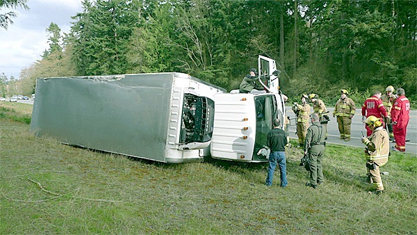 An Island County Sheriff’s deputy enters a box truck after it ended up on its side on Highway 20 late Wednesday afternoon.