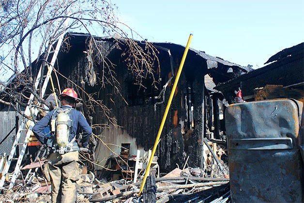 A firefighter surveys the scene of a house fire that killed a resident and injured another Tuesday morning in the Dugualla Bay Heights neighborhood of North Whidbey.