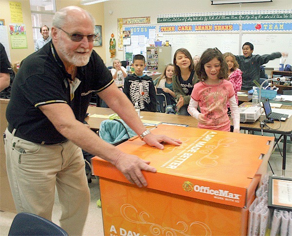 John Mohan from Office Max wheels in a box of school supplies to the joy of student Hailey Gregar and students behind her