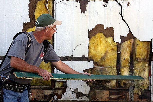 Dave Kelleher uses a board to pull out insulation to reveal a bees nest that needed to be removed from a mobile home at Terry Mobile Park in Coupeville Saturday. Kelleher was part of the Central Whidbey Hearts & Hammers crew that replaced windows.