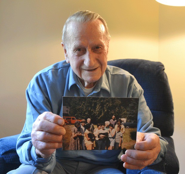 Harold Robinett holds up a photo showing three generations of his family. In the photo are his parents